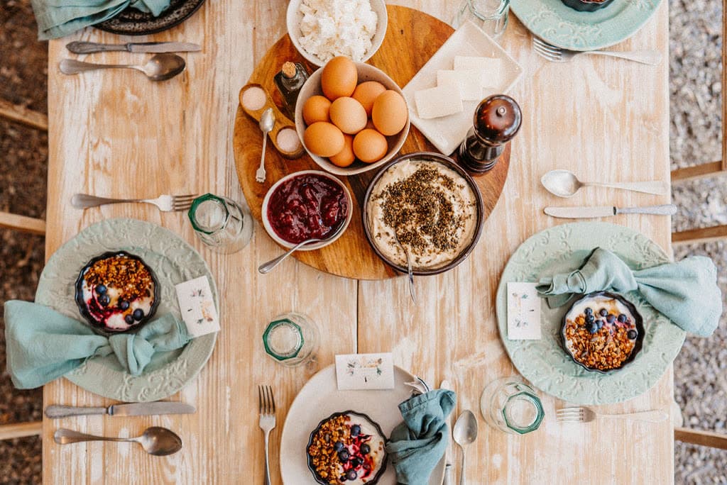 A breakfast table from above, with fruit, granola and teal napkins