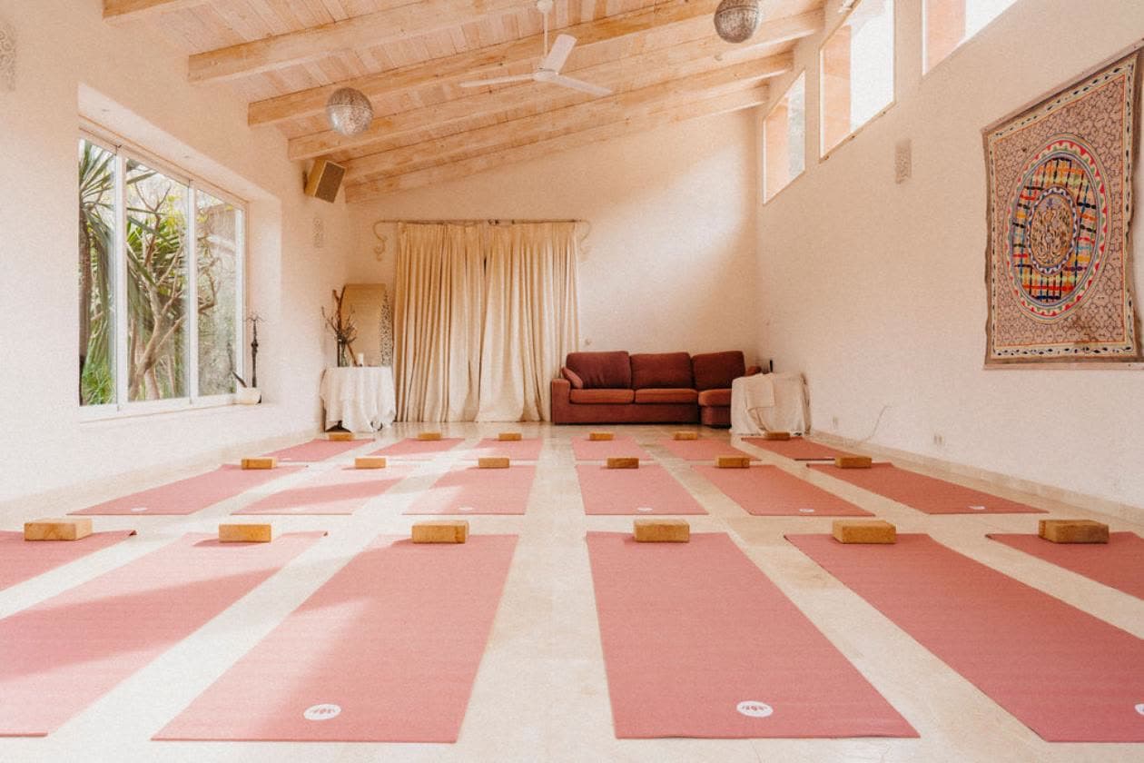 The yoga hall with pink mats laid out under a wooden ceiling