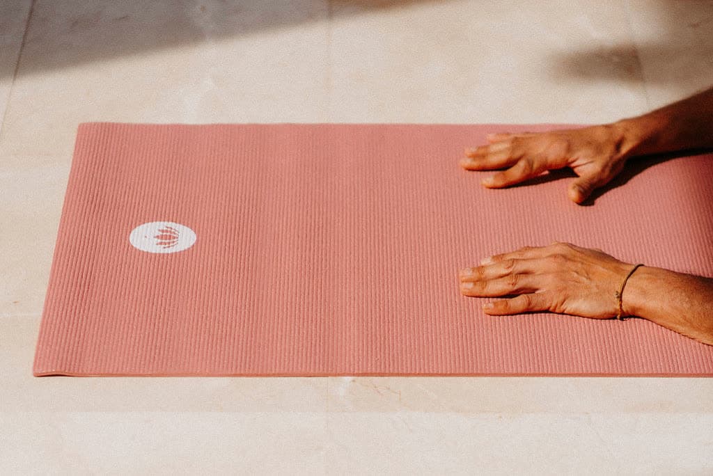 Hands resting on a pink yoga mat