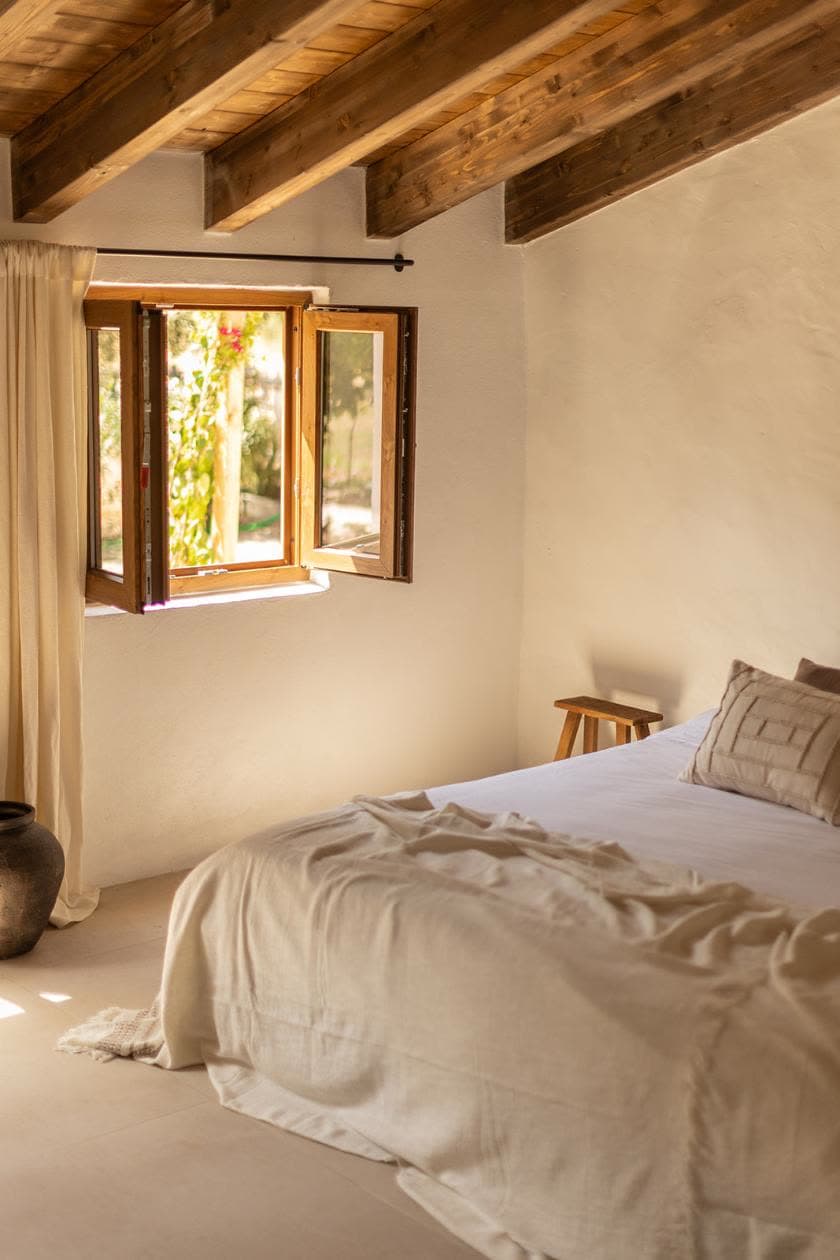 A bedroom with wooden beams and an open window