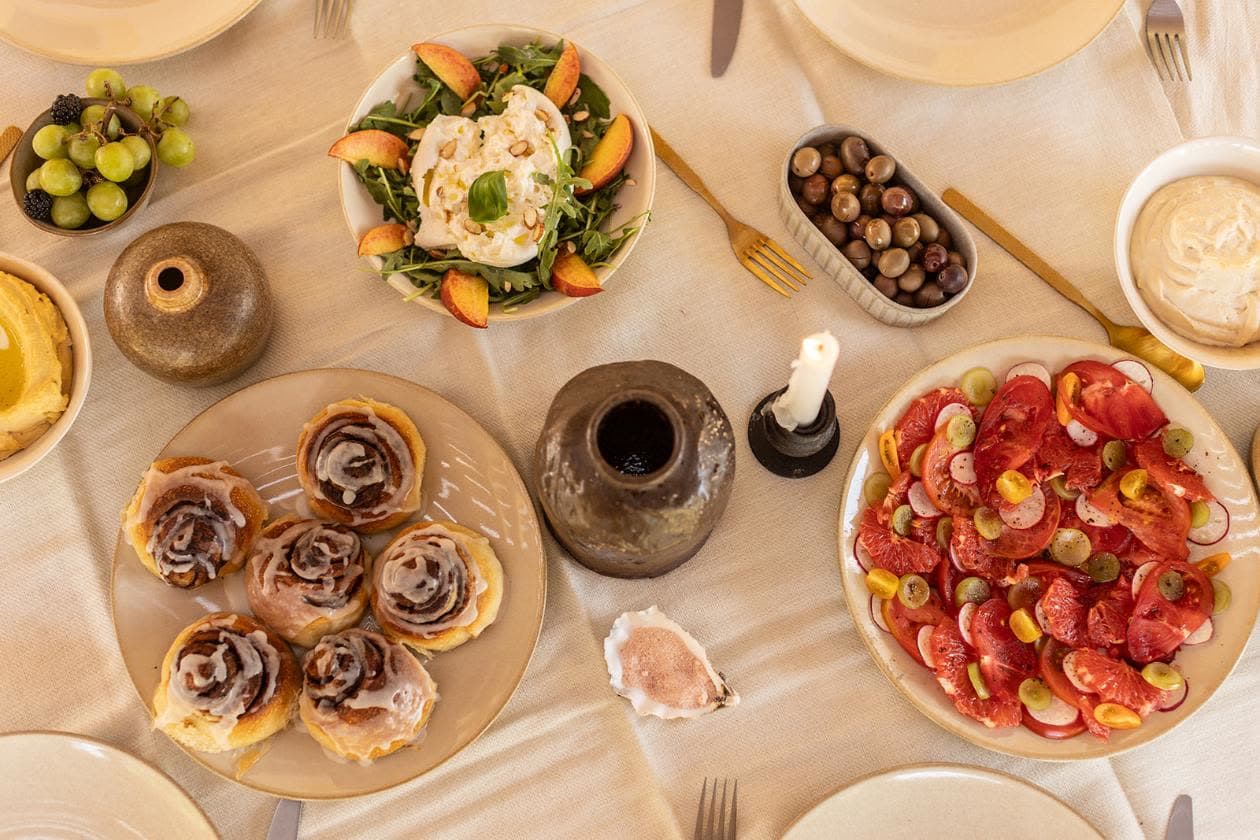 A shared table of salads, pastries and fruit, seen from above