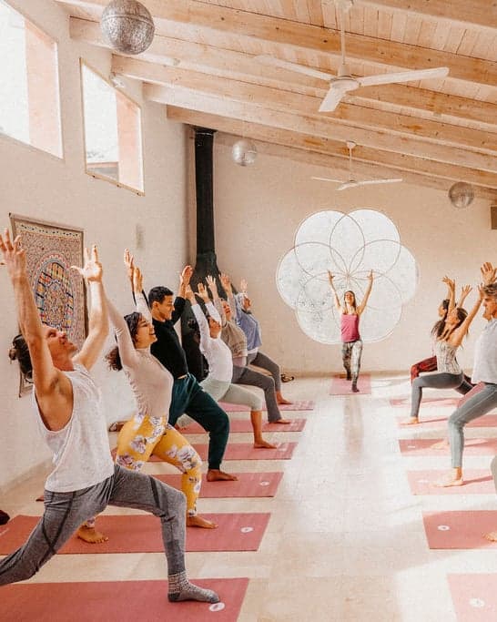 A morning yoga class in the studio, arms raised in a lunge
