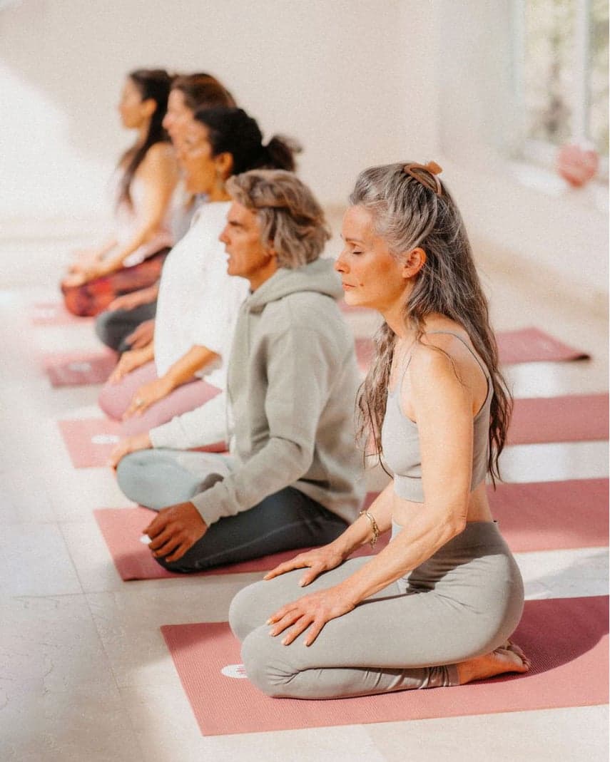 Guests kneeling on their mats with their eyes closed