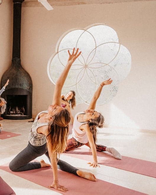 Women in a side stretch on their mats, one arm reaching overhead