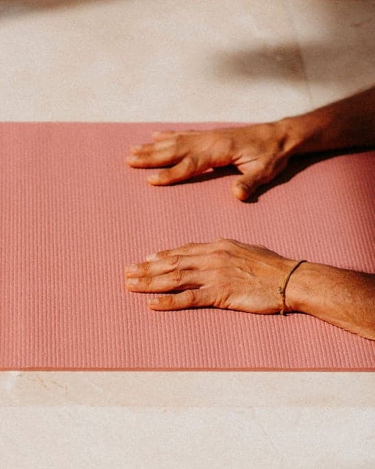 Hands resting on a yoga mat