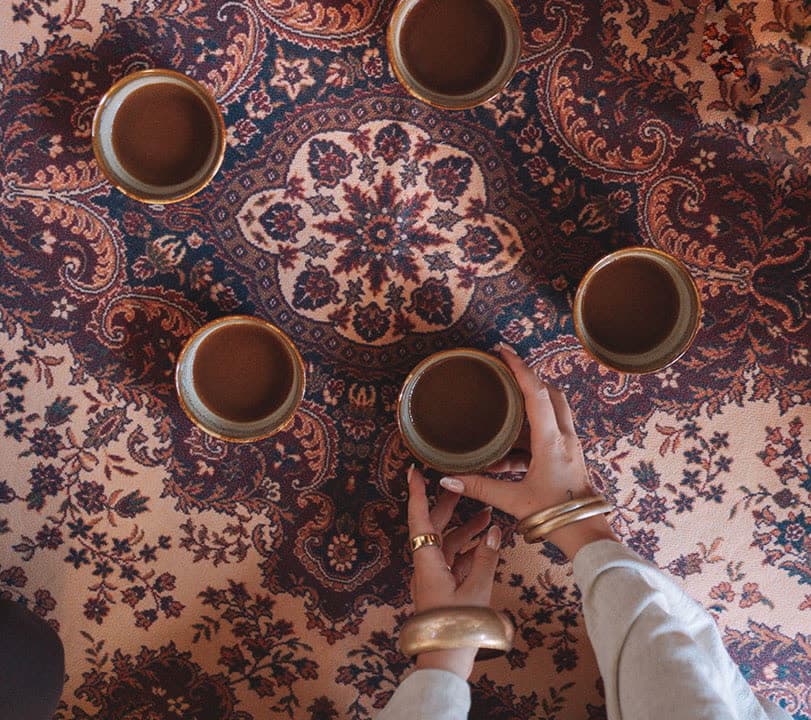 Cups of cacao on a patterned rug, seen from above
