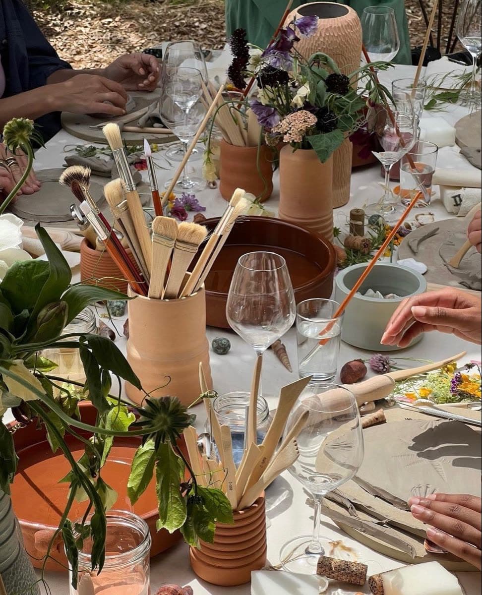 A crafting table with brushes, clay pots and flowers