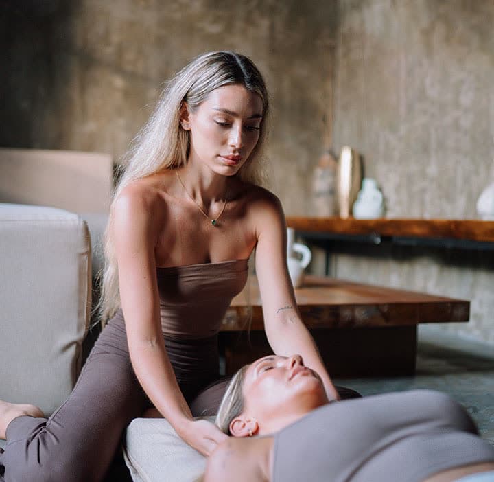 A facilitator resting her hands on a woman lying down during a somatic session